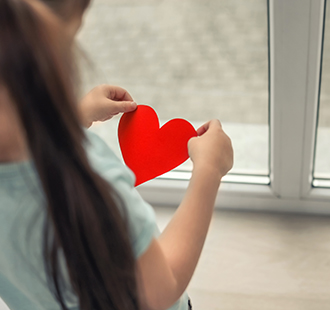 Little girl holding a red paper heart