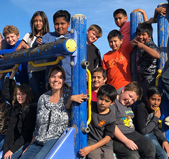 Students and a staff member posing on a playground jungle gym