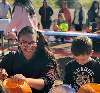 Students carving pumpkins outside