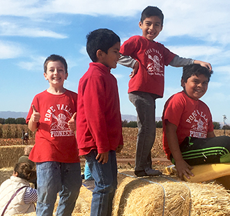 Students posing together on bales of hay outside
